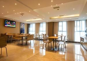 a restaurant with tables and chairs and a flat screen tv at City Comfort Inn Hotel Zigong Wanda Plaza in Shuping