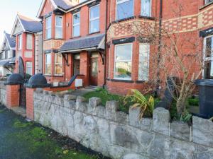 a brick house with a stone retaining wall at Canning Lodge in Colwyn Bay