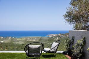 two chairs sitting on a lawn with the ocean in the background at Virtus in Mare in Tsivarás