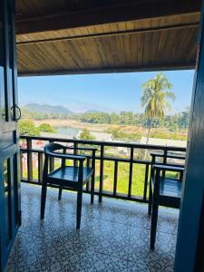 a balcony with two chairs and a view of the water at Zen NamKhan Riverside in Luang Prabang