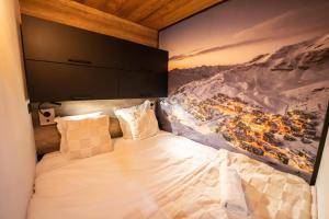 a bedroom with a large bed with a painting on the wall at Val Thorens Cosy Pieds des pistes Centre Val Thorens 2 chbres in Val Thorens