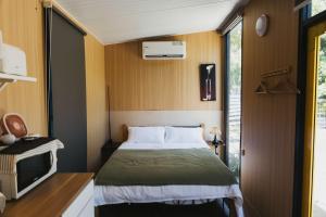 Konggu Valley Retreat Hut X By Tiny Away في T'ou-kou: غرفة نوم صغيرة مع سرير وتلفزيون