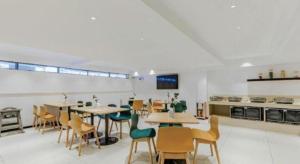 a dining room with tables and chairs and a kitchen at City Comfort Inn Yunfu Xinxing Juncheng Plaza in Xinxing