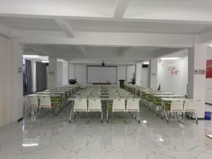 ein Konferenzraum mit Tischen und Stühlen und einer Leinwand in der Unterkunft MIDI Hotel Guangdong Chaozhou Xiangqiao District Hanshan Teachers College in Chaozhou