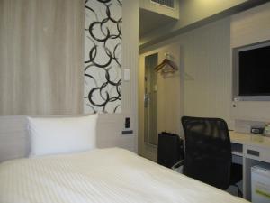 Un dormitorio con una cama, un escritorio y una silla. en Smile Hotel Hachinohe, en Hachinohe