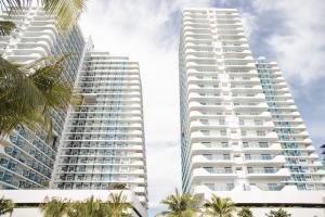 two tall white buildings with palm trees in the foreground at Bali Videl - Studio with Queen Bed & Beach View in San Fernando