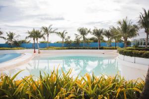 a swimming pool with palm trees and the ocean at Bali Videl - Studio with Queen Bed & Beach View in San Fernando