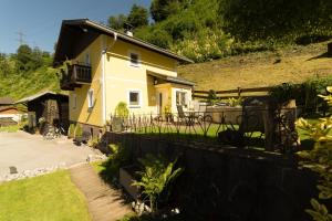 ein gelbes Haus mit einem Zaun neben einem Hof in der Unterkunft Ferienhaus Christine in Taxenbach