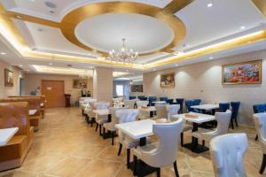 a restaurant with white tables and chairs and a chandelier at Vienna Hotel Jinan Railway Station in Jinan