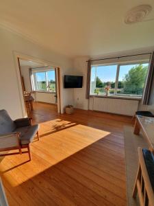 Una sala de estar con suelo de madera y dos ventanas. en Lovely Holiday Home With Views Of Fields, en Lebøl