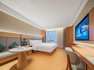 une chambre d'hôtel avec un lit et une télévision à écran plat dans l'établissement JI Hotel Chengdu Wenjiang University Town, à Chengdu