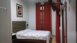 Anciejo inn ll في ليما: غرفة نوم بها سرير وستارة حمراء