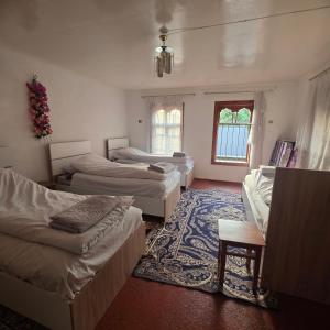 Zimmer mit 3 Betten und einem Teppich in der Unterkunft Sim Guesthouse in Sım