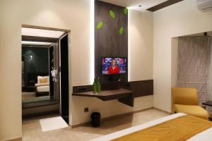 ein Schlafzimmer mit einem Bett und einem Fernseher an der Wand in der Unterkunft Hotel The Leaf in Aurangabad