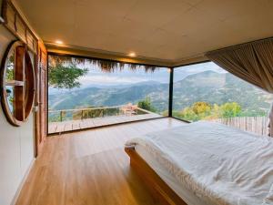 een slaapkamer met een bed en een groot raam bij แล้วแต่เพื่อนวิลล่า in Ban Huai Khai