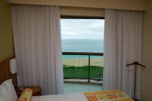 a bedroom with a window with a view of the ocean at Gloria Garden Suites in Macaé