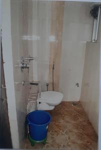 a bathroom with a toilet and a blue bucket at Hotel Welfare Club in Bhilai