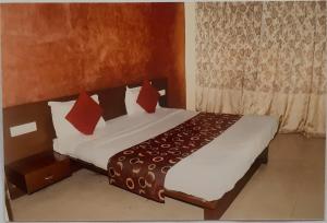 a bedroom with a bed with white sheets and red pillows at Hotel Welfare Club in Bhilai