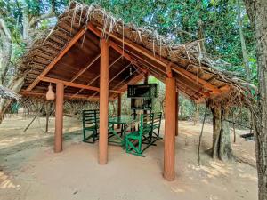 a hut with a thatched roof and a green table at Yala Wild House in Yala