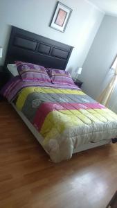 uma cama com um edredão colorido num quarto em Hotel con C em Concepción