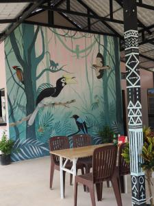 Palm & Pepper - Koh Rong في سيهانوكفيل: طاولة وكراسي أمام جدارية للطيور