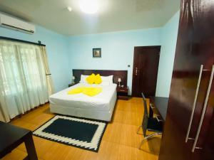 Premium City Guesthouse في غابورون: غرفة نوم بسرير ابيض عليها مناشف صفراء +3 صور