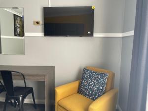 a living room with a yellow chair and a tv at Parkway Motel in Queanbeyan +71 photos