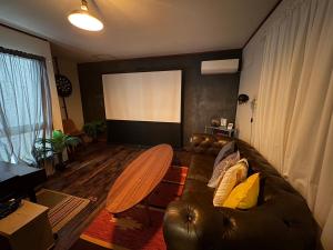 ein Wohnzimmer mit einem Ledersofa und einem Bildschirm in der Unterkunft OSAKA DOSHIN HOUSE in Osaka