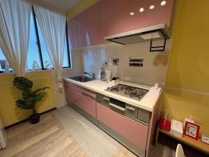 eine kleine Küche mit Herd und Spüle in der Unterkunft OSAKA DOSHIN HOUSE in Osaka