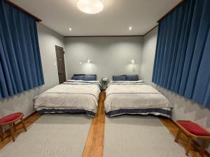 zwei Betten in einem Zimmer mit blauen Vorhängen in der Unterkunft OSAKA DOSHIN HOUSE in Osaka