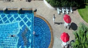 a group of people under umbrellas near a swimming pool at Regency Hotel in Ma Yu