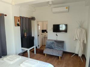 a bedroom with a bed and a tv and a chair at ม่วนใจ๋ปันสุข โฮมสเตย์แอนคาเฟ่ Muanjai punsuk homestay and cafe in Chom Thong