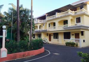 Villa Neesham Grande في بيناوليم: عمارة صفراء كبيرة فيها نخيل وشارع