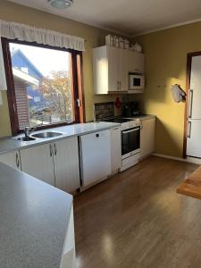 a kitchen with white cabinets and a large window at Guesthouse Leon in Tórshavn +1 photo