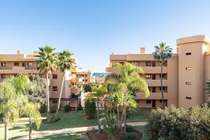 an apartment building with palm trees in front of it at Azul Cala Mijas Apartment in La Cala de Mijas