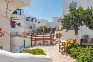 a courtyard with chairs and trees and white buildings at Apollon Rooms in Pollonia