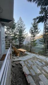 a stone patio with a bench and a fence at Eleven 11 cafe and stay in Jibhi