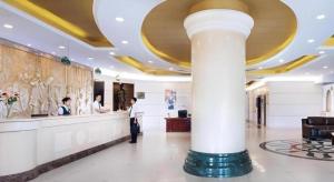 a man standing in a hotel lobby with a counter at Vienna Hotel Shanxi Taiyuanfu West Street in Taiyuan