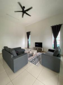 a living room with two couches and a ceiling fan at Banglo Jasin Perdana in Bemban