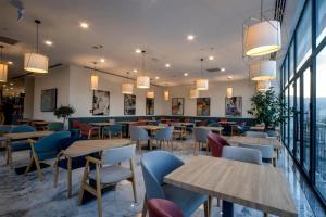 een restaurant met tafels, stoelen en ramen bij Hampton By Hilton Denizli in Denizli