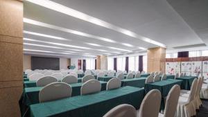 a conference room with green and white chairs and a screen at Zhaoqing Shanshui Fashion Hotel Duanzhou Road Branch in Zhaoqing