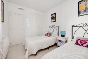 two beds in a room with white walls at CB Living - Apartment with roof terrace Aguamarina in Orihuela Costa +23 photos
