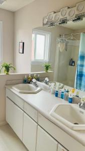 un bagno con due lavandini e un grande specchio di warm house2 a Coquitlam