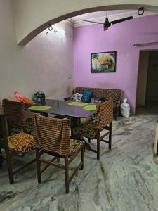 a table and chairs in a room with a purple wall at Krushna Boys Pg in Ahmedabad