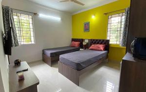 a living room with two beds and a tv at Krushna Boys Pg in Ahmedabad