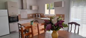 Una cocina con una mesa con un jarrón de flores encima. en Gîte les lys à Lignières Chatelain, en Lignières-Châtelain
