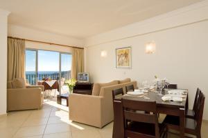 a dining room and living room with a table and chairs at Silmar in Albufeira