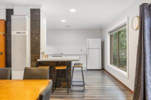 una cocina con electrodomésticos blancos, mesa y sillas en Kangaroo House, en Halls Gap 16 fotos más