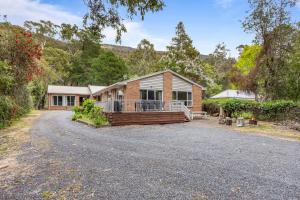 una casa de ladrillo con un porche en un camino de entrada en Kangaroo House, en Halls Gap
