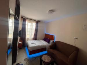 a small bedroom with a bed and a chair at Pearl Studio in Machakos